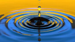Closeup of water droplet and ripples - water is reflecting blue and gold colors