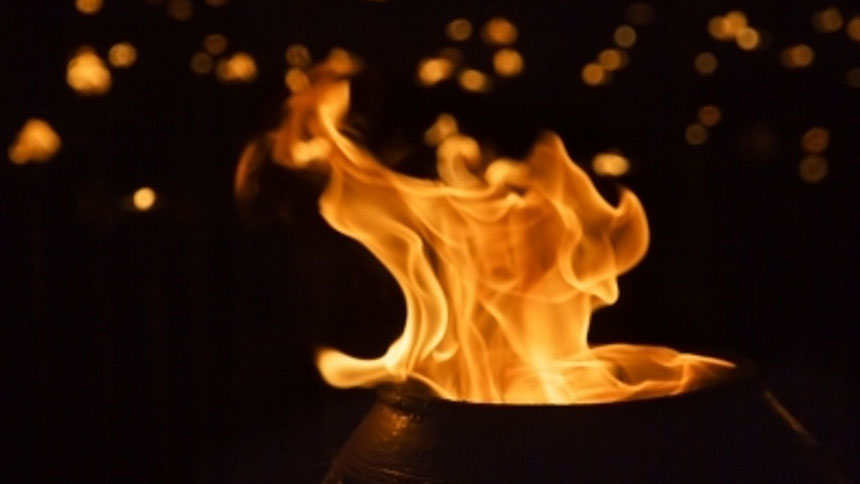 Flames emerging from a clay pot; dark background with other lights