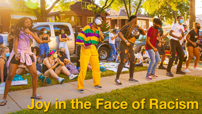 Protesters in Chicago dancing on a sidewalk in bright clothing | "Joy in the Face of Racism" overlaid in gold text