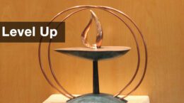 The UUCP chalice sitting on a stand with a wood paneled background.
