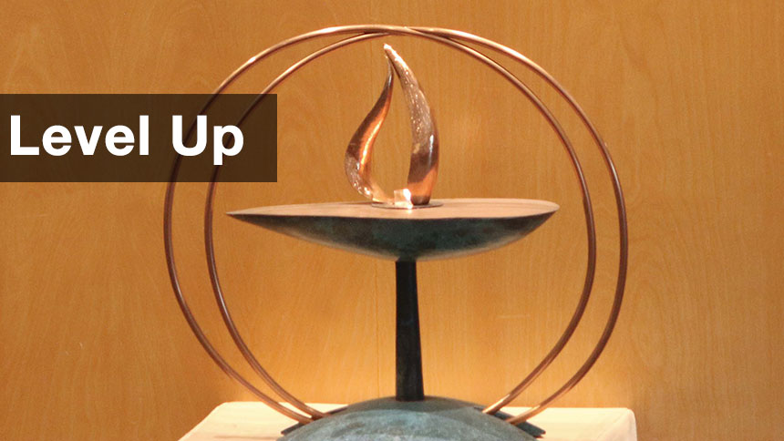The UUCP chalice sitting on a stand with a wood paneled background.