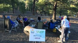 Outdoor group members gathered at the Sunset Crater campground; "UUCP Outdoor Group" sign in the foreground