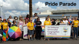A gathering of people at the pride parade holding a UUCP banner.